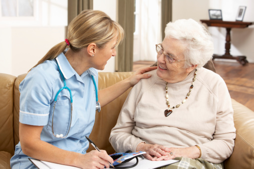 Una joven auxiliar de enfermería con un paciente anciano