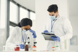 Hombre y mujer con bata blanca de laboratorio haciendo análisis de laboratorio