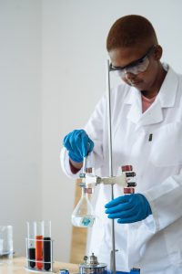 Focused researcher in protective eyewear doing test with liquids