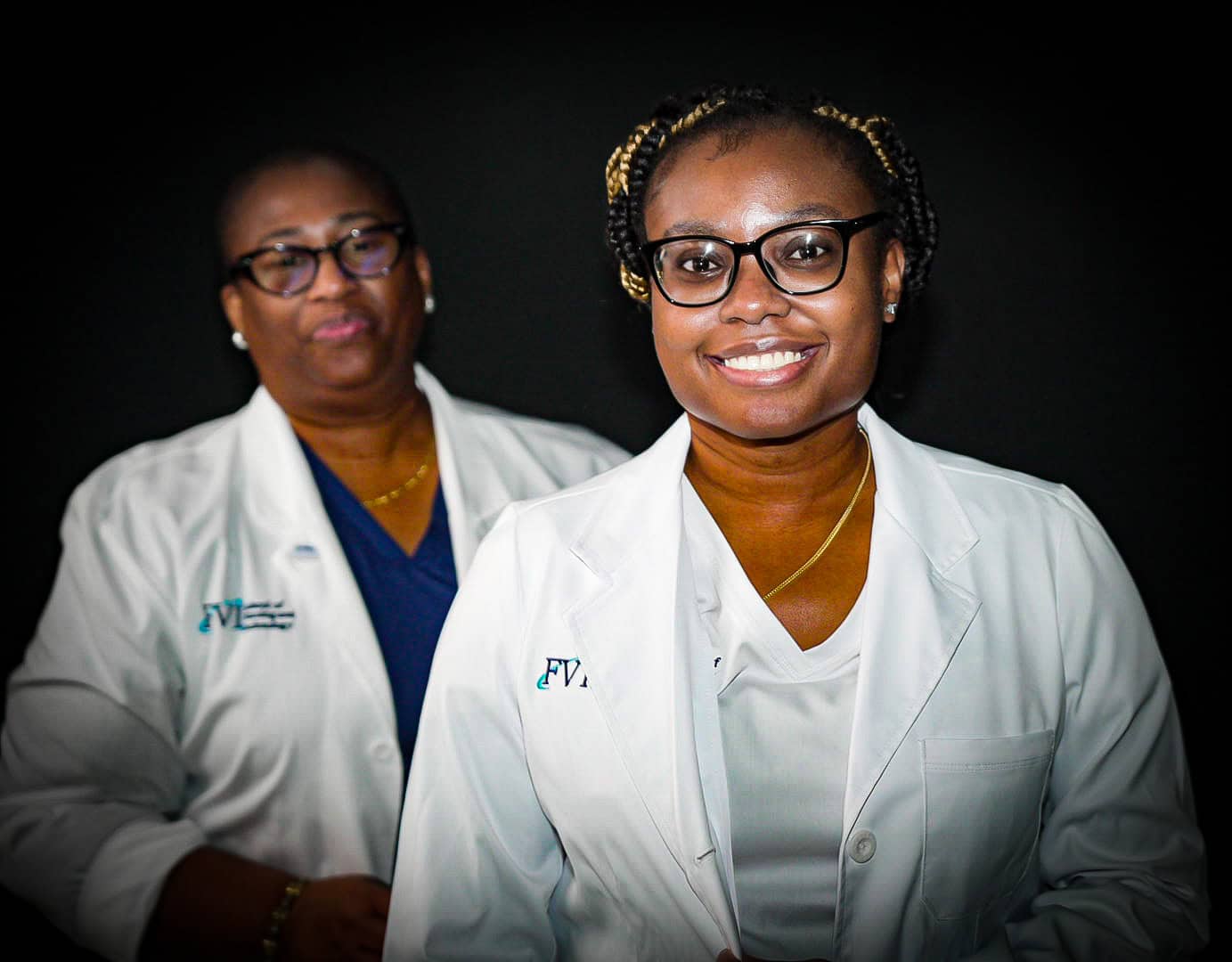 Two students smiling in white scrubs