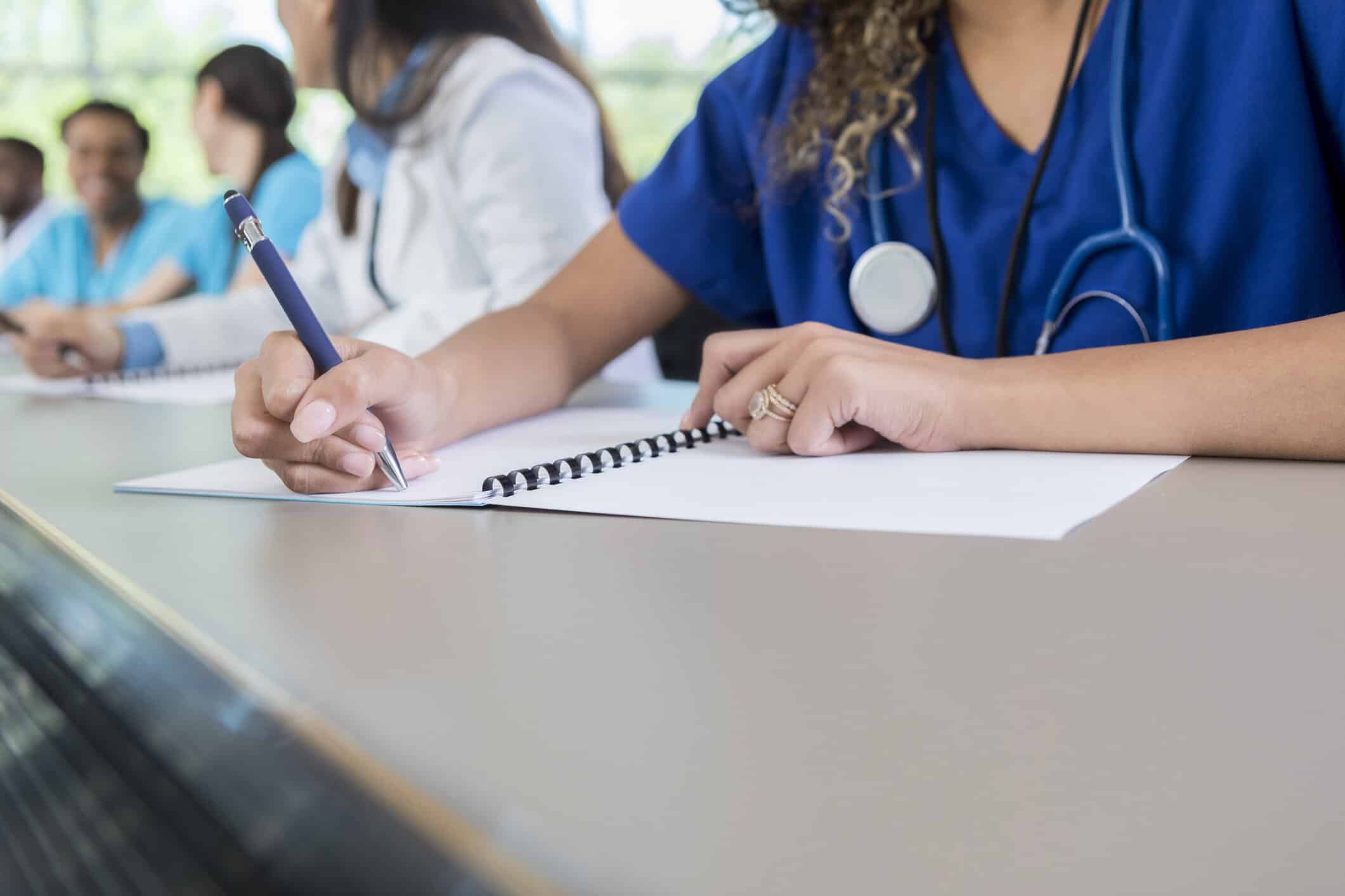 Unrecognizable medical student writes in class workbook