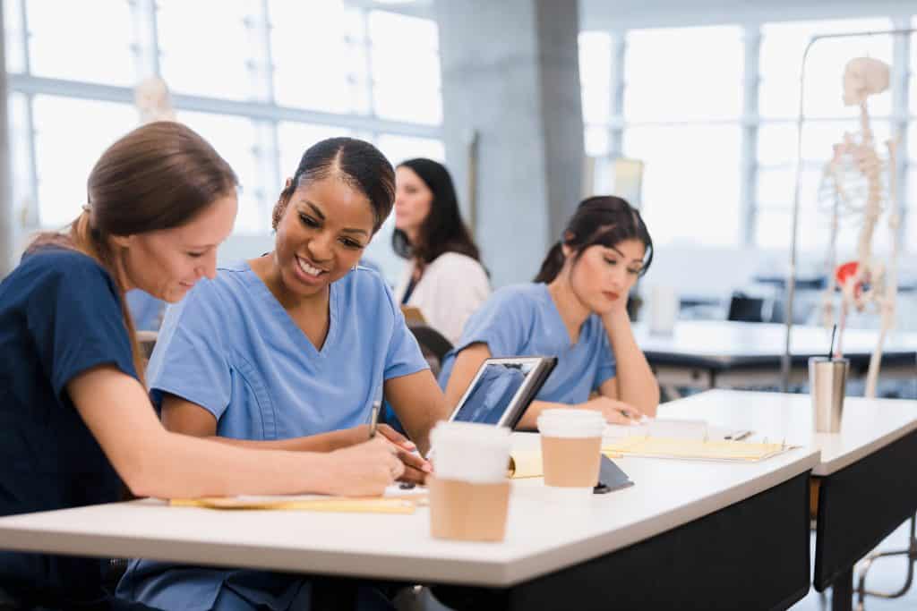 Two mid adult female nursing students co-operate on classwork