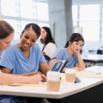 Two mid adult female nursing students co-operate on classwork