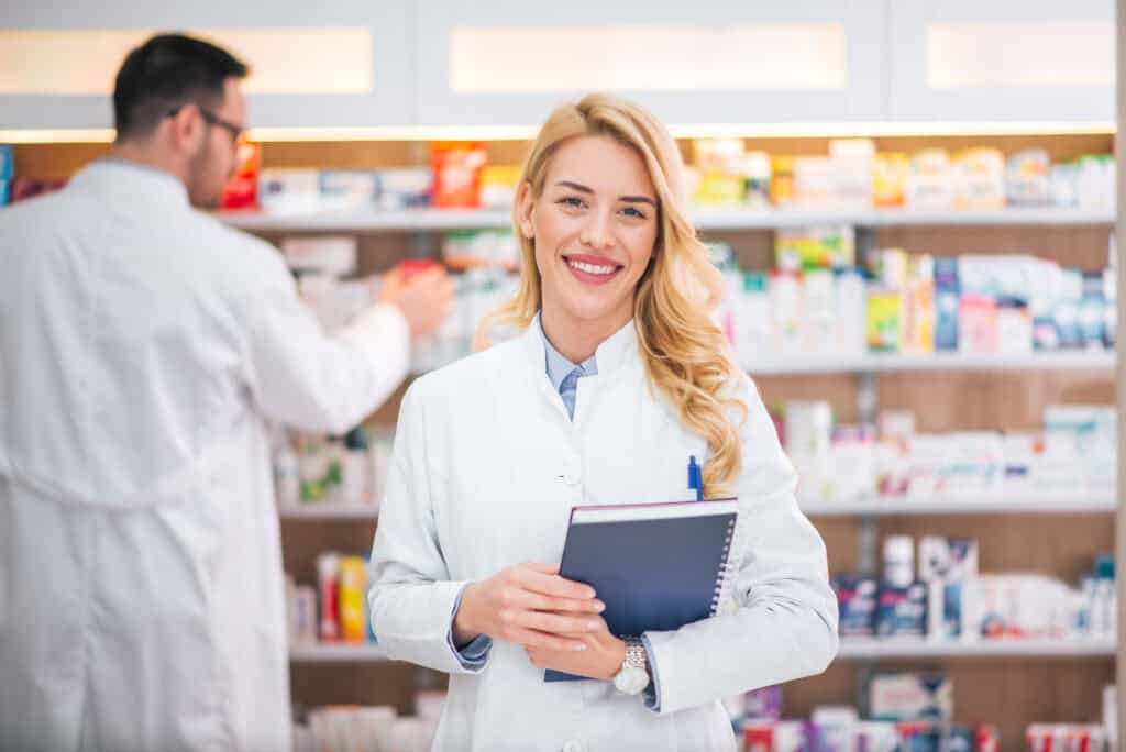 A pharmacy technician smiling at the camera in a real world pharmacy