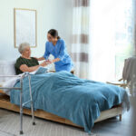 A nursing assistant home health aide assisting a client in their bed at their home