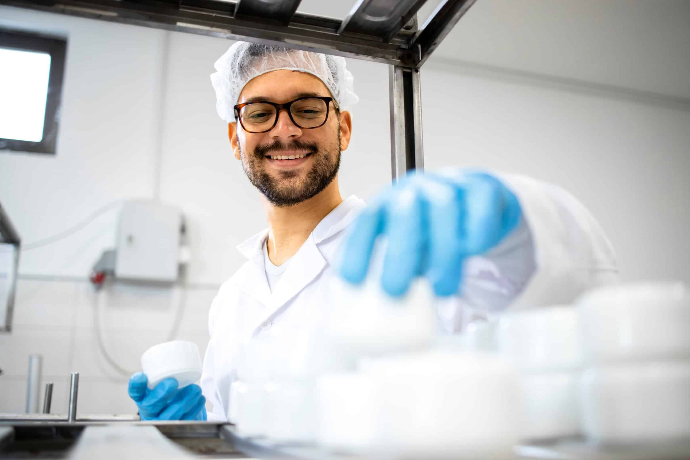 Close up view of pharmaceutical worker technologist working in cosmetics factory with healthcare creme products.
