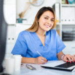 A  healthcare worker smiling at the camera working in an office setting