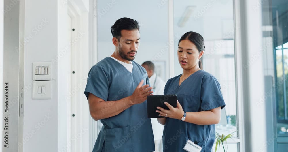 2 healthcare workers consulting an ipad in a hospital setting