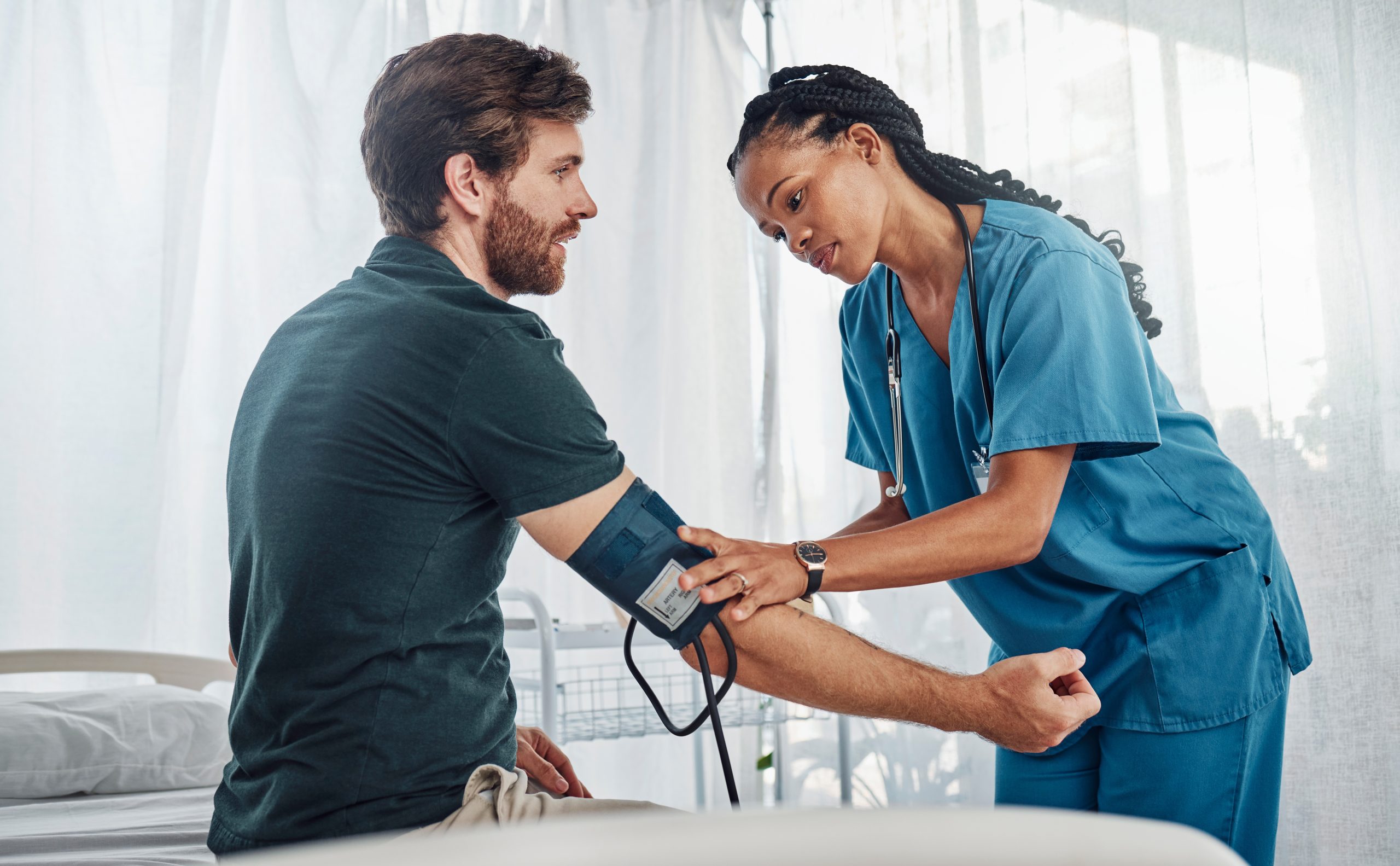 Nurse and man with blood pressure test in hospital for heart health or wellness. 