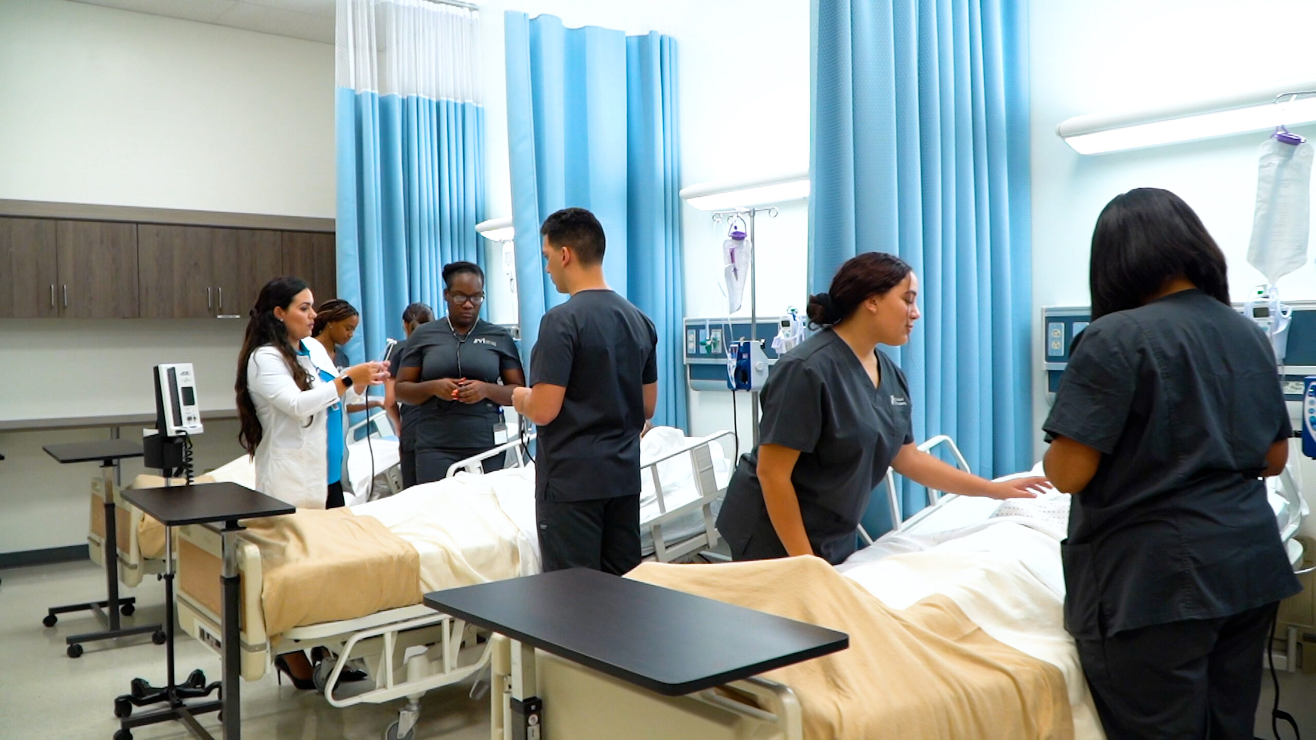 Students are practicing in an FVI skills lab under the supervision of a member of the nursing faculty