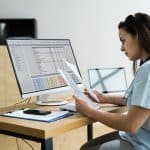 A healthcare worker sitting at a computer looking at documents
