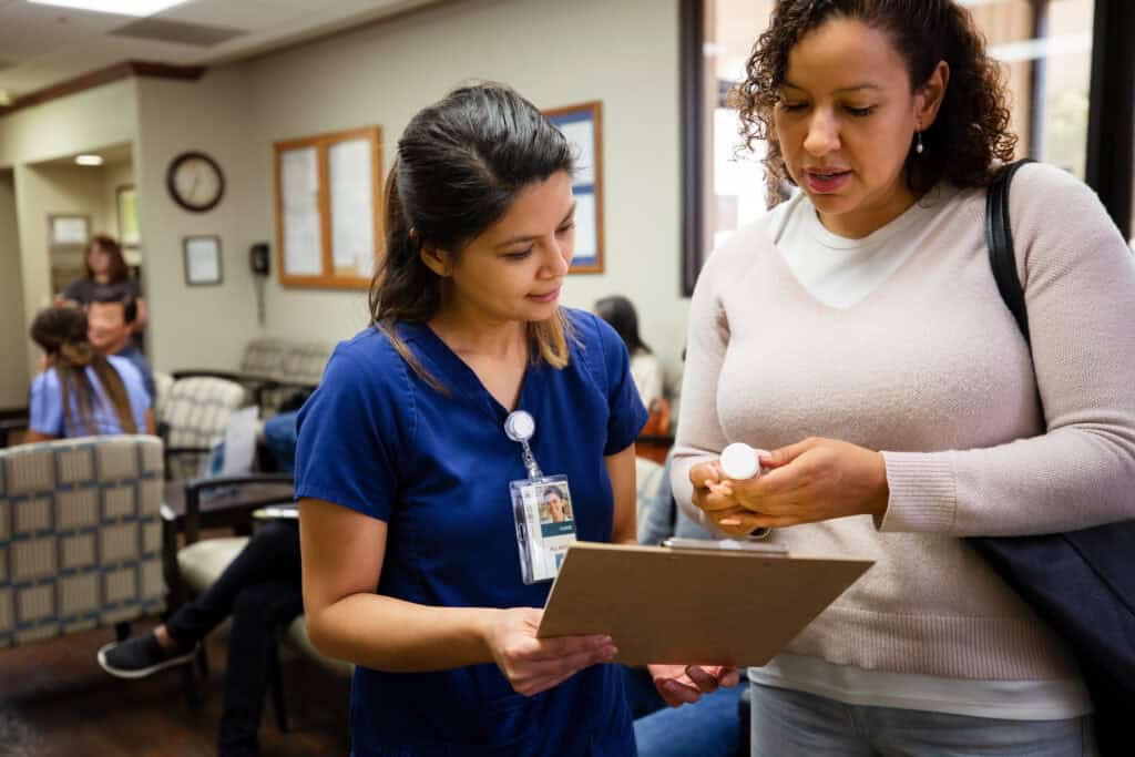 Nurse talks with female patient about prescription medication