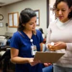 Nurse talks with female patient about prescription medication