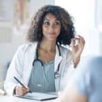 florida health coach sitting at a table with a pen in hand ready to write sitting across from a client