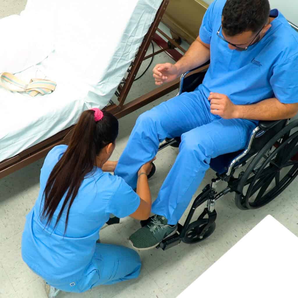 Two students practice using a wheelchair