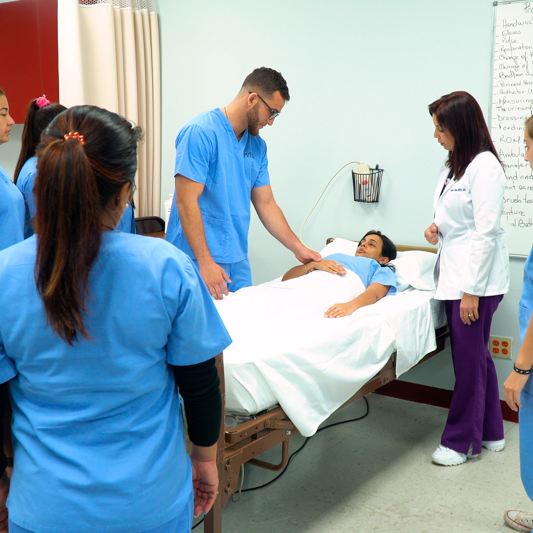 Students gather around a medical simulation with a faculty member