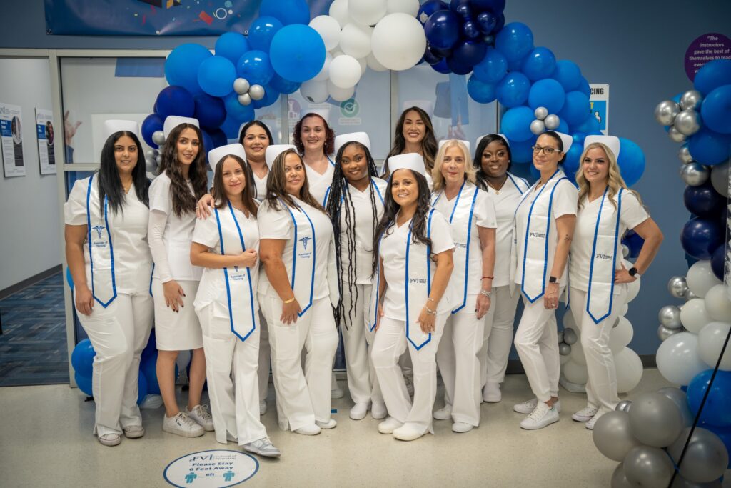 FVI Nursing graduates posing in front of a balloon arch in the FVI Miramar lobby after a Pinning Ceremony