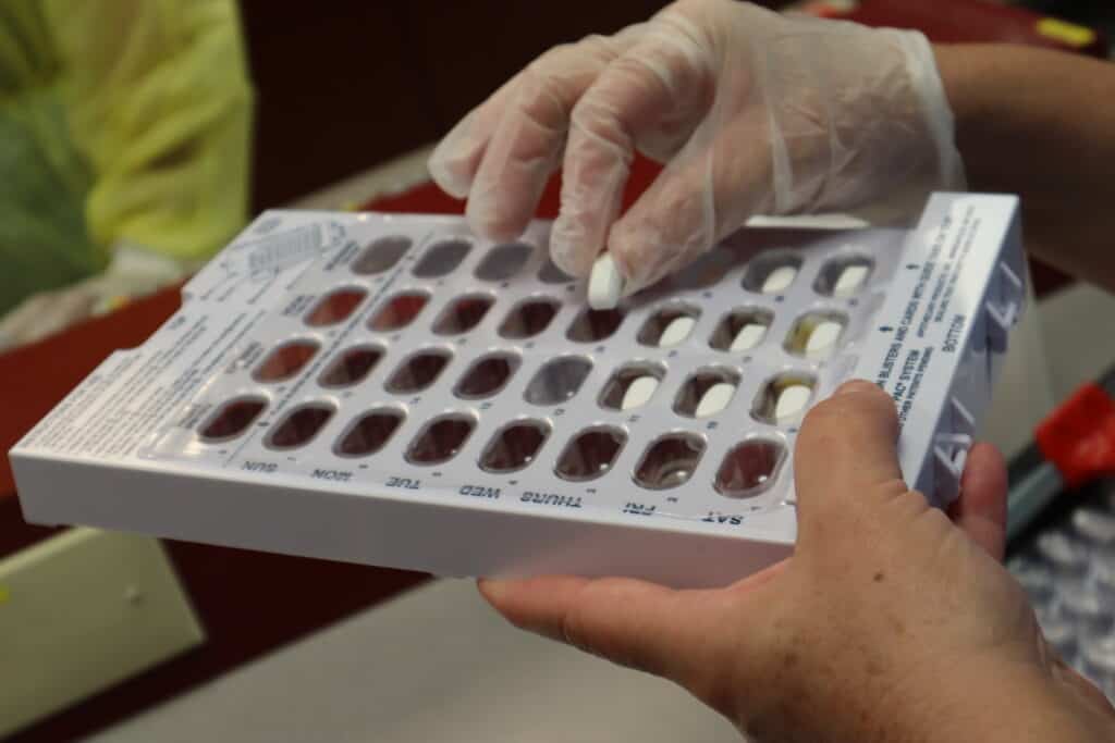 hands putting pills inside tray