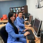 Two FVI students in scrubs working at the lab