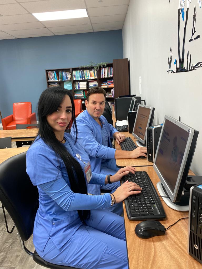 Two FVI students in scrubs working at the lab