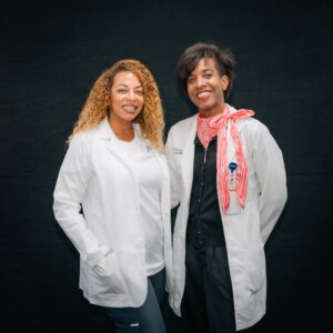 nursing students posing in front of other nursing students pracitcing