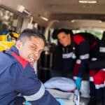 EMT team assisting with patient transport in ambulance