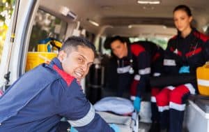 Confident EMT professional standing inside an ambulance with arms crossed.
